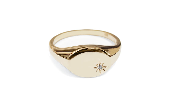 Solid yellow gold signet ring with an oval head with a star set white diamond on the bottom right corner