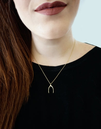 female wearing yellow gold wishbone pendant necklace