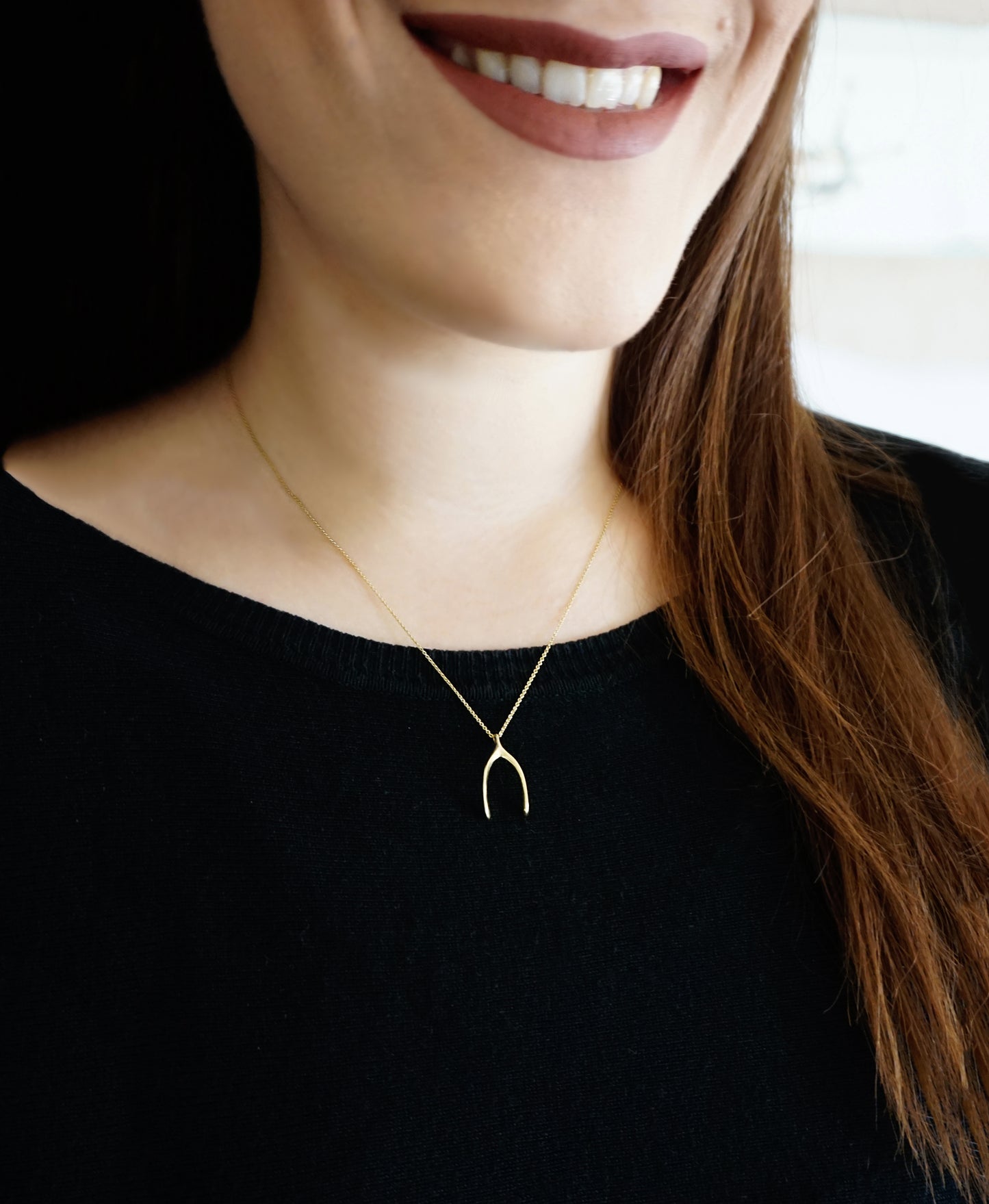 woman wearing solid yellow gold wishbone pendant necklace