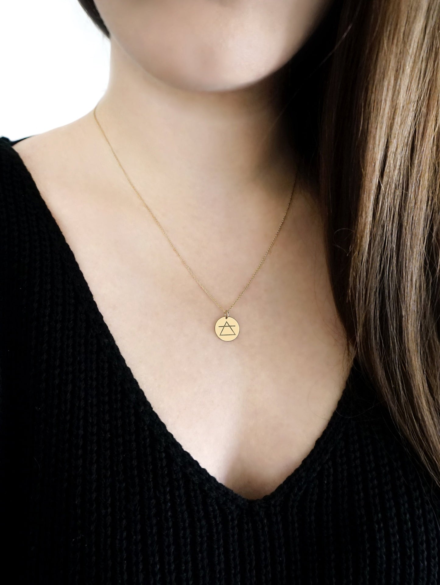 female wearing a yellow gold necklace with a 14mm disc pendant engraved with the air element