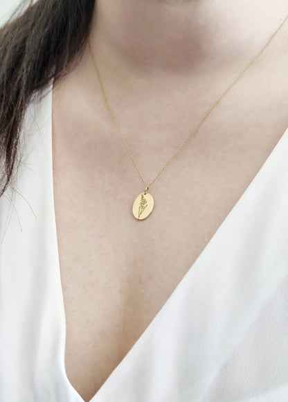 woman wearing solid yellow gold oval pendant necklace engraved with a Gladiolus the birth flower of August