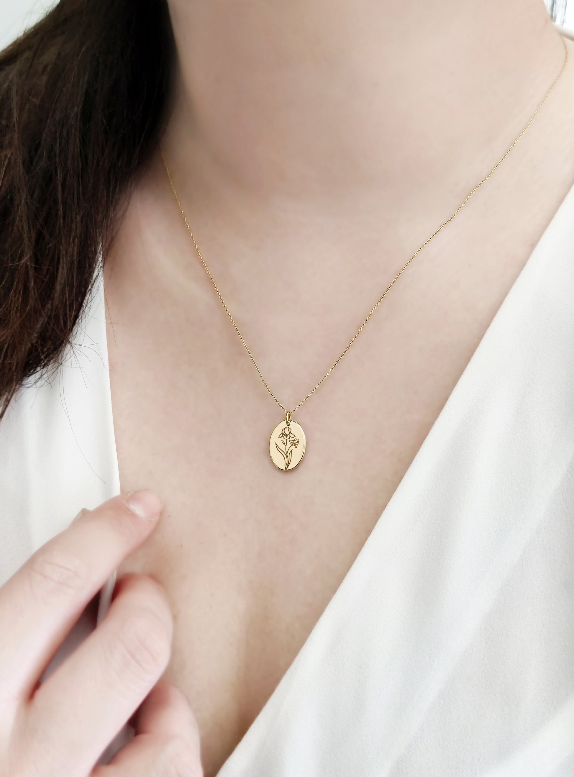 female wearing gold oval pendant necklace engraved with an Iris the birth flower of February