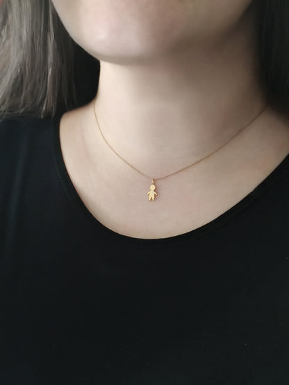 close up of a woman's neck wearing a gold necklace with a tiny boy charm set with a tiny diamond