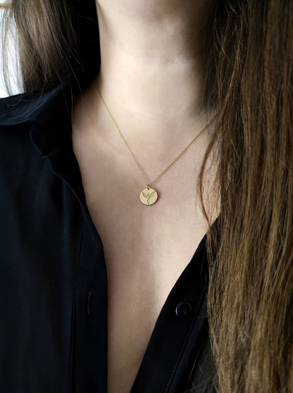Woman wearing a necklace with a disc pendant engraved with a phoenix firebird