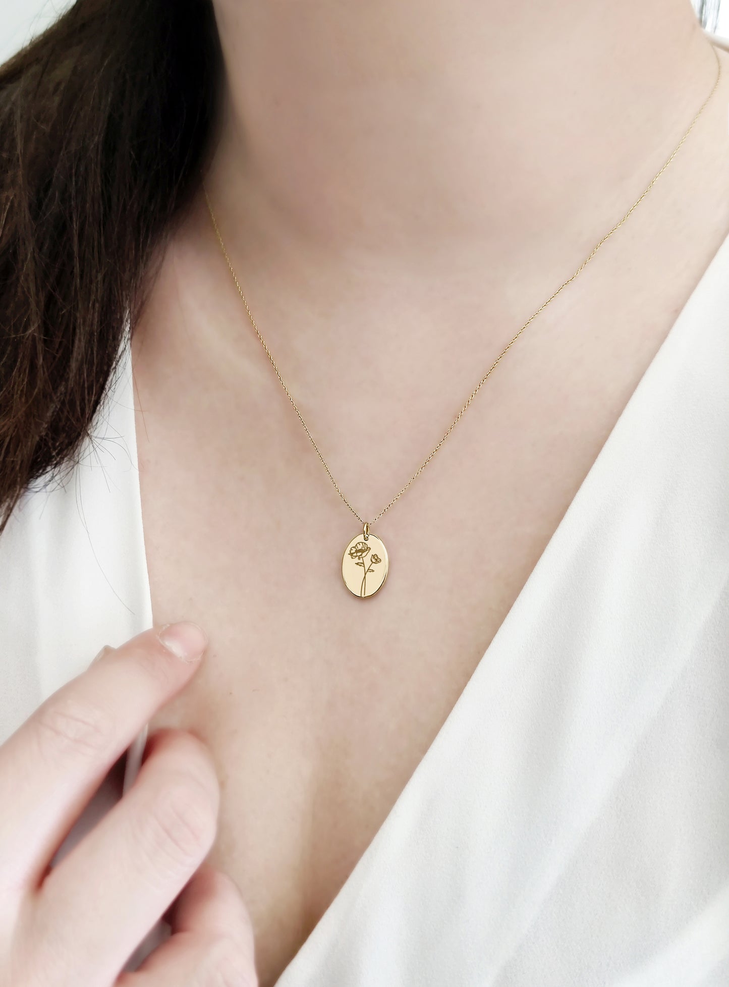 woman wearing solid yellow gold oval pendant necklace engraved with a Poppy the birth flower of August