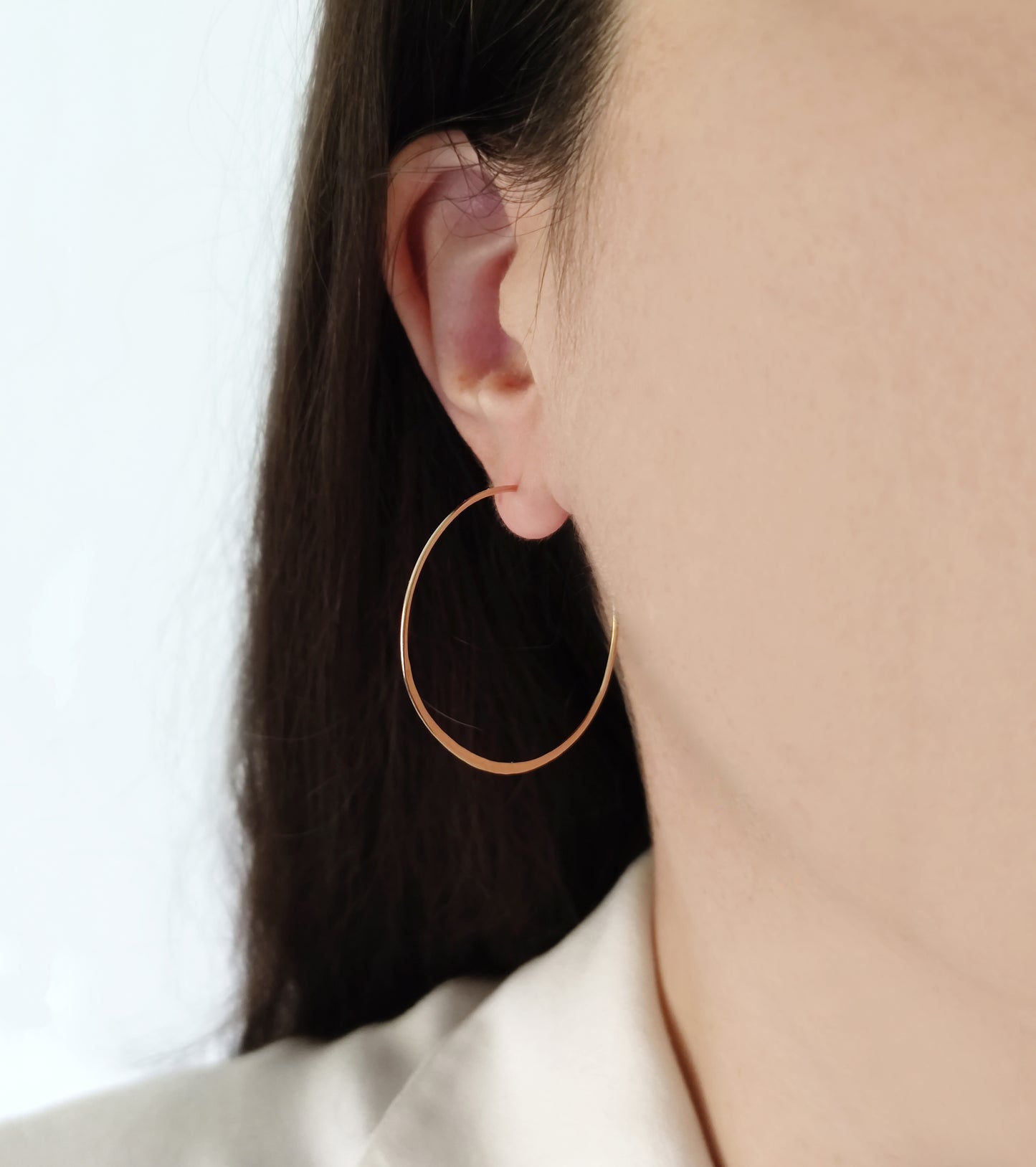 close up a woman's ear wearing yellow gold 40mm diameter thin hoop earring with flattened bottom