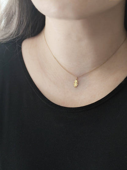 close up of a woman's neck wearing a gold necklace with a tiny girl charm set with a tiny diamond