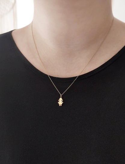 close up of a woman's neck wearing a gold necklace with a tiny girl charm set with a tiny diamond