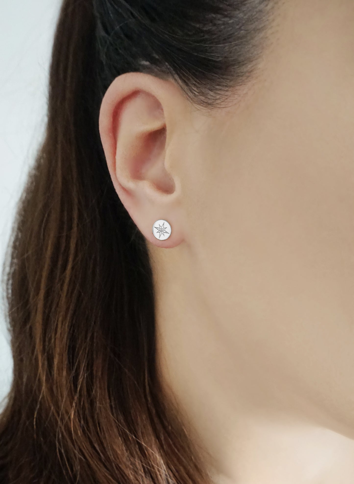 female wearing solid white gold north star disc stud earrings set with a tiny diamond in the center