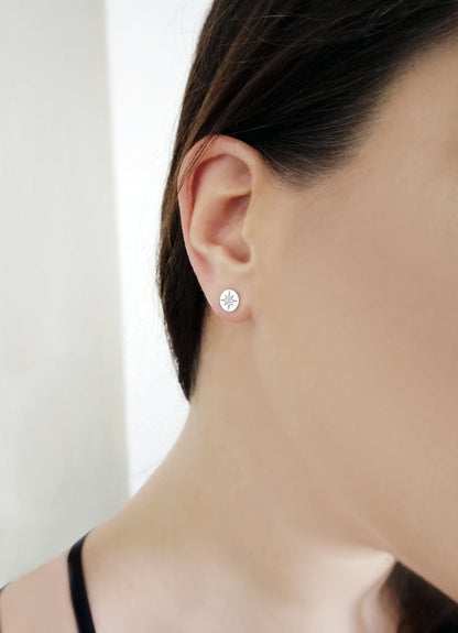 woman wearing solid white gold north star disc stud earrings set with a tiny diamond in the center