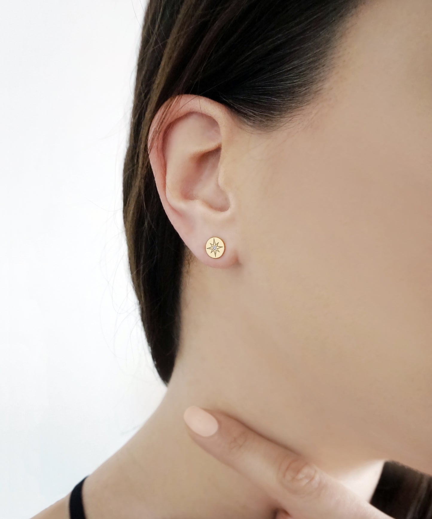 female wearing solid yellow gold north star disc stud earrings set with a tiny diamond in the center