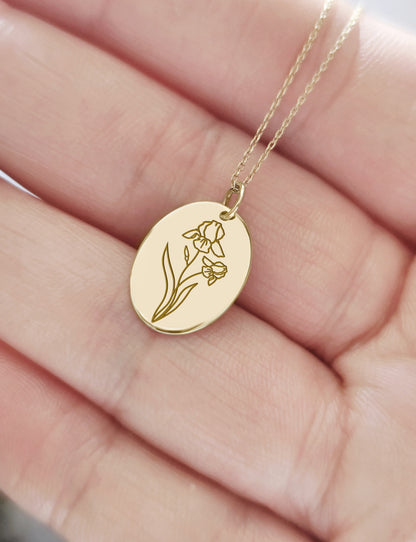 hand holding gold oval pendant necklace engraved with an Iris the birth flower of February for size reference