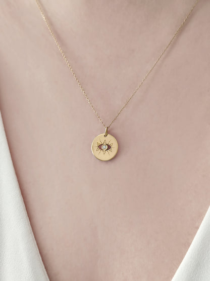 close up of a female wearing gold evil eye disc pendant necklace set with a diamond in the center