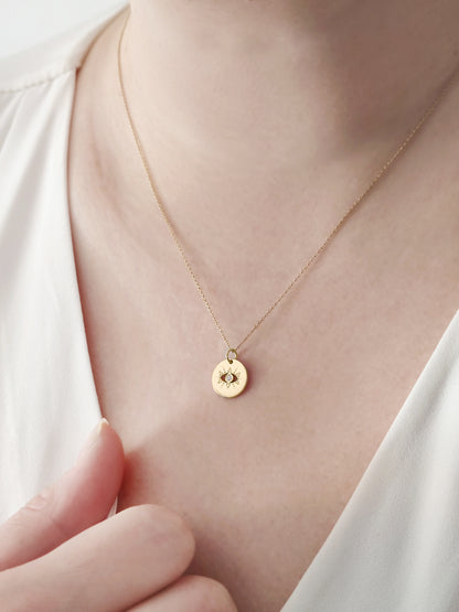 female wearing gold evil eye disc pendant necklace set with a diamond in the center