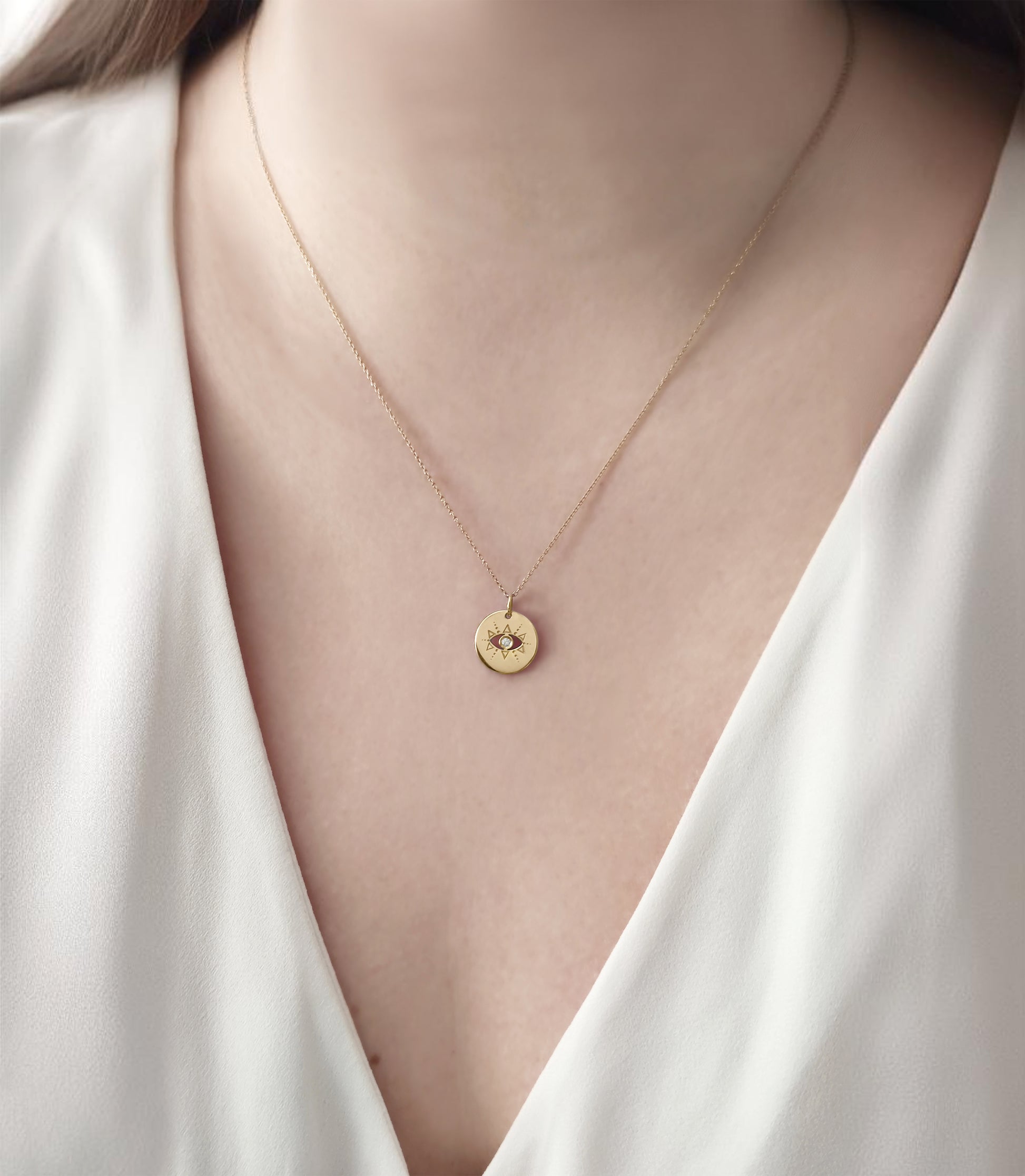 woman wearing gold evil eye disc pendant necklace set with a diamond in the center