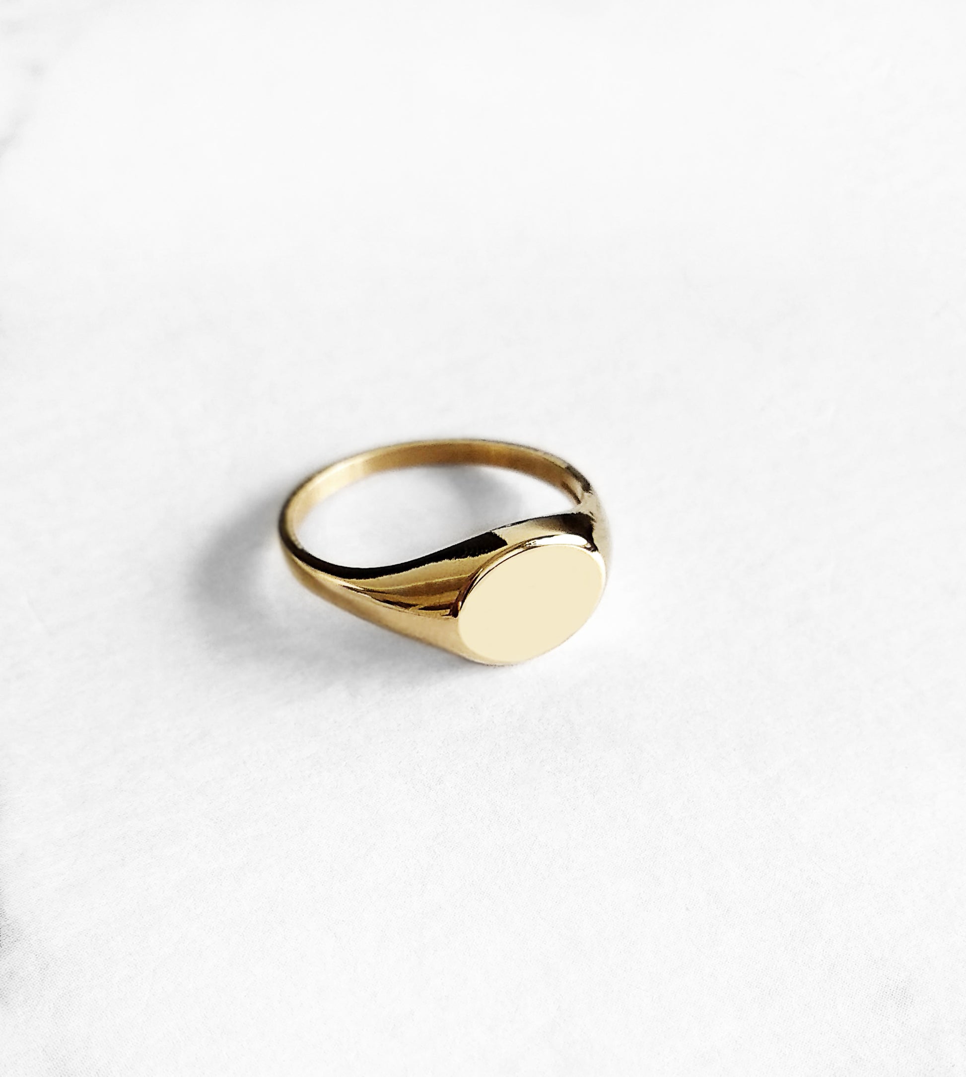 three quarter view of a solid yellow gold dainty oval signet ring