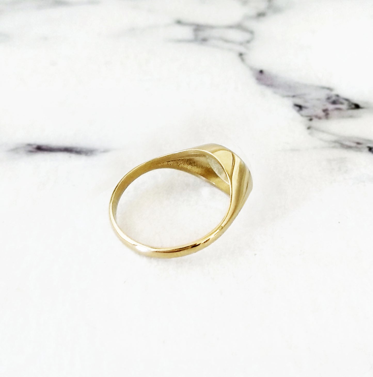 view of the semi hollow back of a solid yellow gold dainty oval signet ring