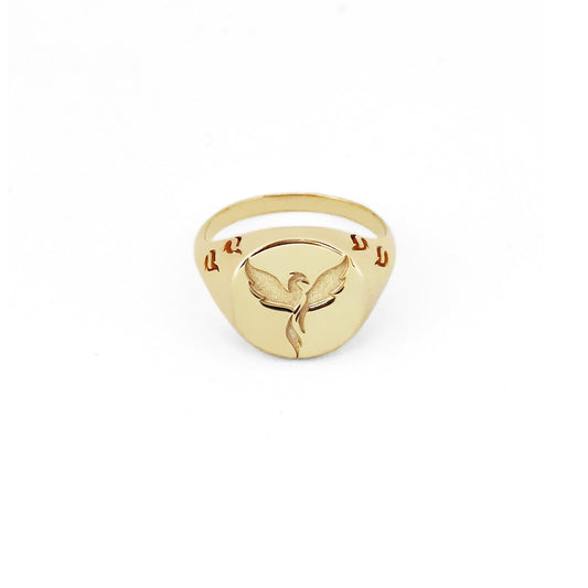 solid yellow gold polished round signet ring engraved with a phoenix firebird rising with flame cutouts around the base of the ring's head