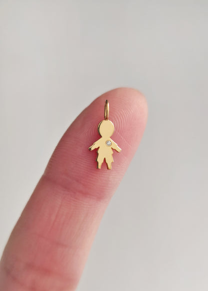 close up of a fingertip holding a tiny gold boy outline charm set with a tiny diamond for size reference